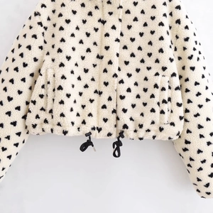 Cremefarbene Fleecejacke mit schwarzem Herzprint, Reißverschluss und Kordelzugsaum