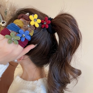 Détail de chouchous fleurs en velours avec strass portés sur une queue de cheval