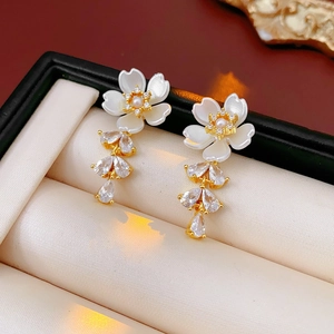 Detailed close-up of golden flower earrings with zircon tassels and white pearl accents