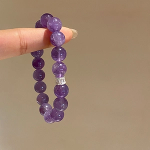 Macro shot of purple amethyst beaded bracelet with textured silver metal charm