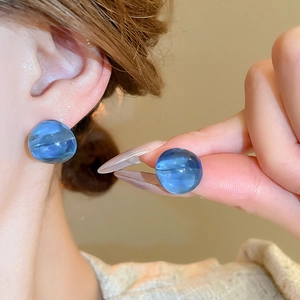 Detailed close-up of blue resin spherical earrings with transparent cloudy texture