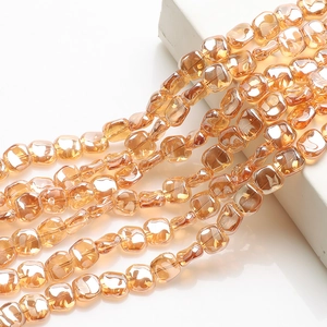 Detailed view of faceted amber glass beads strands hanging on white geometric prop