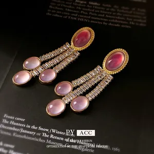 Orecchini vintage dorati con pietre rosa ovali e zirconi su uno sfondo nero elegante