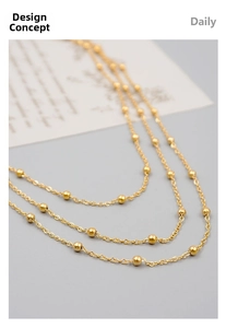 Detailed close-up of golden beaded triple-layer chain necklace in minimalist design