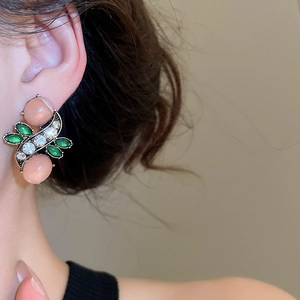 Close-up of vintage resin floral earrings with pink stones and green leaves on a model