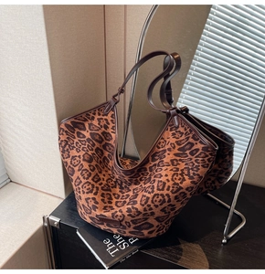 Detail of leopard print tote bag with brown faux leather handles on a black surface