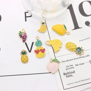 Flat lay of colorful enamel fruit charms including pineapple and peach for DIY jewelry