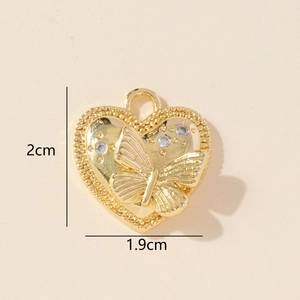 Macro shot of 2cm golden heart pendant with embossed butterfly and clear crystals