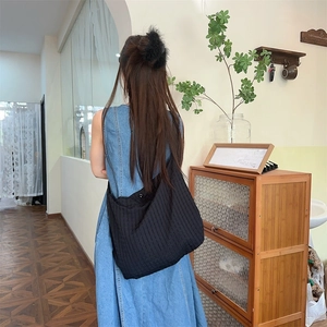 Détail du sac à bandoulière en tissu noir avec des motifs de rayures verticales
