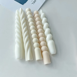 Macro shot of minimalist spiral and beaded pillar candles in warm Morandi cream tones