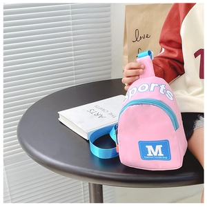 Gros plan d'un sac bandoulière rose pour enfant en nylon avec sangle bleue et texte sport