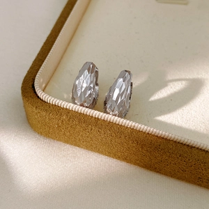 Detail view of silver geometric faceted huggie earrings on premium velvet texture