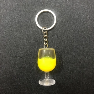 Macro detail of wine glass keychain with liquid yellow resin on black leather base