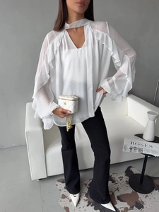 Detail shot of white chiffon shirt with elegant ruffles and long bell sleeves on a model