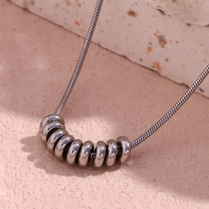 Close-up of a silver snake chain necklace with eight interlocking circular pendants