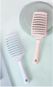 Detailansicht rosa und weißer gebogener Skelettbürsten für Kopfhautmassage und Styling