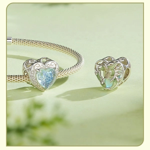 Detail of S925 sterling silver heart charms with blue gemstone and leaf pattern