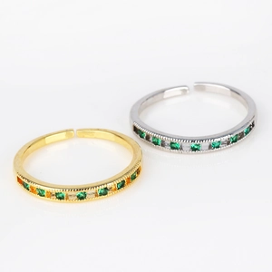 Detail of adjustable gold and silver rings with emerald green zircon paving