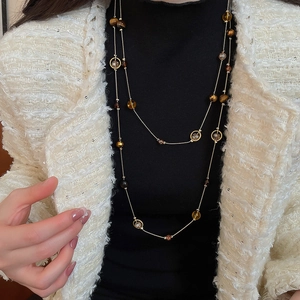 Detail einer mehrlagigen Goldhalskette mit Tigerauge-Perlen und Kristallen an einem Model