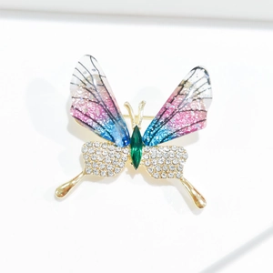 Macro detail of butterfly brooch with colorful enamel wings and green gemstone body
