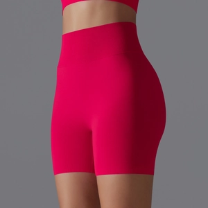 Detail view of high-waist seamless red yoga shorts showing ribbed waistband and peach lift fit