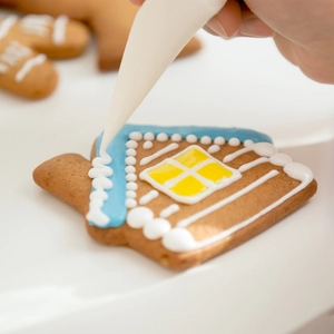 Detail of icing piping technique on a gingerbread house shaped stainless steel cookie cutter