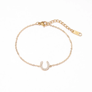 Golden stainless steel U-shaped horseshoe bracelet with clear zircon stones on white background