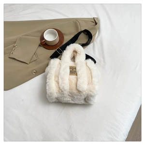 Close-up of cream fuzzy tote bag with Have a Nice Day tag and black nylon strap