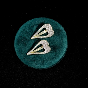 Golden heart-shaped hair clips with sparkling crystals on a green velvet base