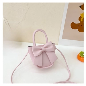 Pink mini bucket bag featuring large bow and sleek top handle in a gift setting