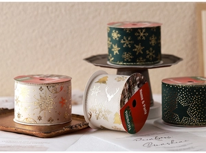 Detail of dark green and cream Christmas ribbons with gold foil reindeer and snowflakes