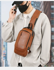 Brown faux leather chest bag for men with USB port shown in an urban city setting