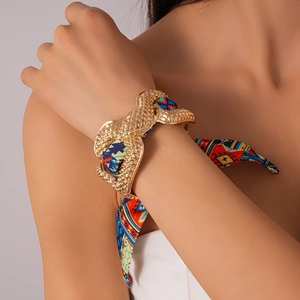 Close-up of golden textured cuff bracelet with an ethnic printed silk ribbon wrap