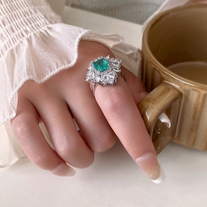 Dettaglio di un anello in argento con gemma verde quadrata e grappoli di zirconi lucenti