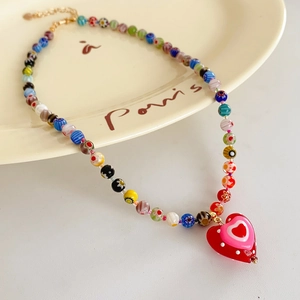 Detailed macro of colorful millefiori glass beads and red heart pendant on necklace