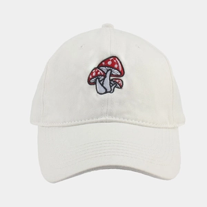 Dettaglio di un cappello da baseball bianco con tre funghi rossi ricamati sul fronte