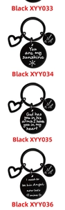 Close-up of black stainless steel keychains with heart charm and engraved love messages