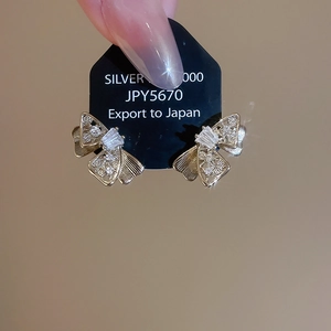 Detail of gold bow earrings featuring cubic zirconia pavé and Silver 925 hallmarks