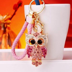Detail of owl keychain with pink rhinestones, braided leather rope and gold metal