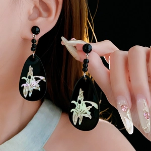 Detail of vintage geometric black teardrop earrings with white floral inlay pattern
