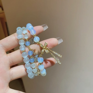 Detail of multi-layer beaded bracelet with blue cat eye stones and gold star moon pendants