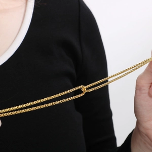 Minimalist gold box chain bracelet in stainless steel held by hand showing flexibility