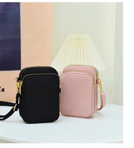 Detailed view of black and pink nylon mini crossbody phone bags with triple gold zippers