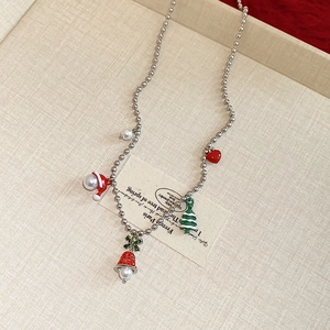Detail of Christmas necklace with colorful enamel charms like tree and bells on a tray
