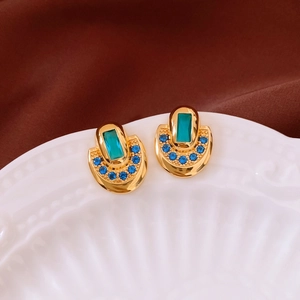 Vue détaillée de boucles d'oreilles vintage dorées avec pierre verte et cristaux bleus