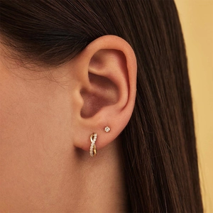 Close-up of gold-plated silver twisted hoop earrings with diamonds on ear lobe