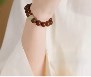 Detail of dark brown wooden prayer beads with a green jade accent on a wrist