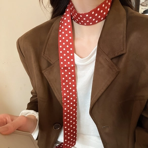 Detail of red polka dot silk scarf necklace worn with a vintage brown suede blazer