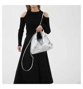 Detail of silver crossbody tote bag featuring decorative metal butterflies and smooth finish
