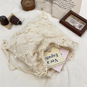 Detailed view of the creamy white canvas drawstring bag with decorative fringe texture